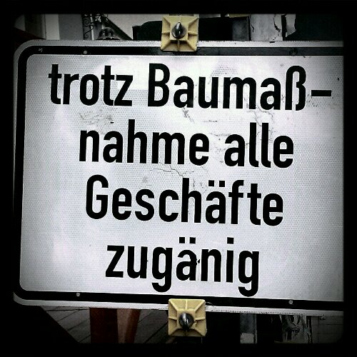 Schild mit Aufschrift: Trotz Baumaßnahme alle Geschäfte zugänig